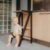 Dijete sjedi na sklopivom crnom Montessori tornju za učenje s jabukom u ruci, ultralagani drveni model bez montaže